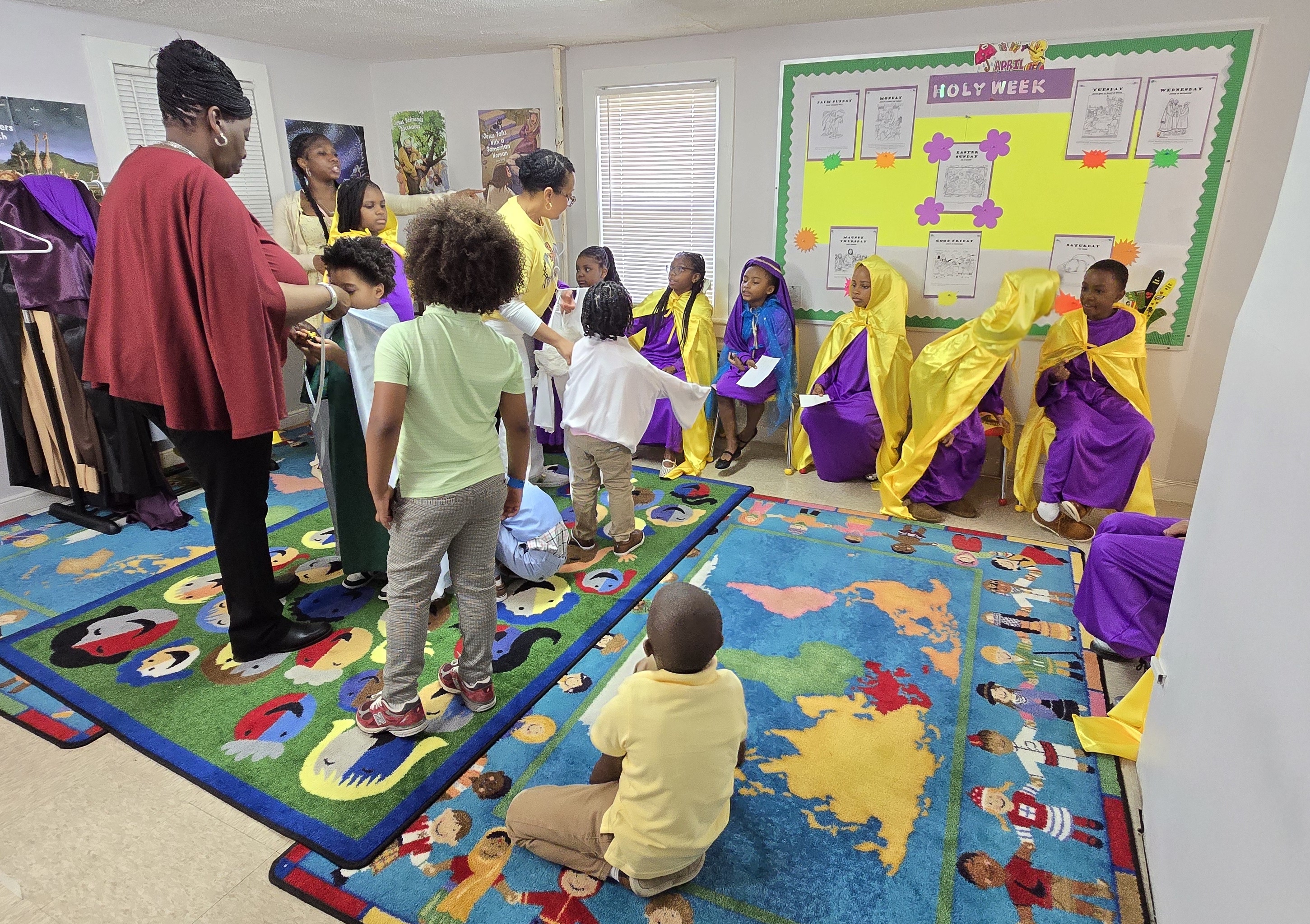 group of children seated in purple and gold robes against wall in decorated room